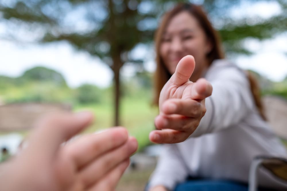Due persone che si stanno per toccare con le dita. Una è fuori campo e si vede solo la sua mano, l'altra è sfocata. Il fuoco è sulle mani.